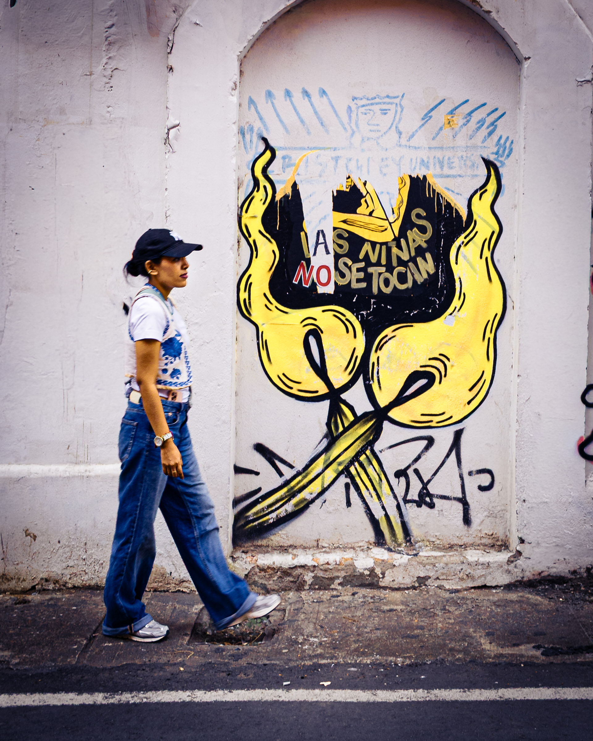 Mural urbano LAS NIÑAS NO SE TOCAN e indiferencia de transeúnte